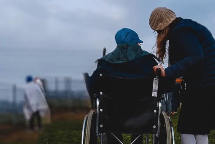 wheelchair, person in wheelchair, outdoor, winter clothing, caregiver helping