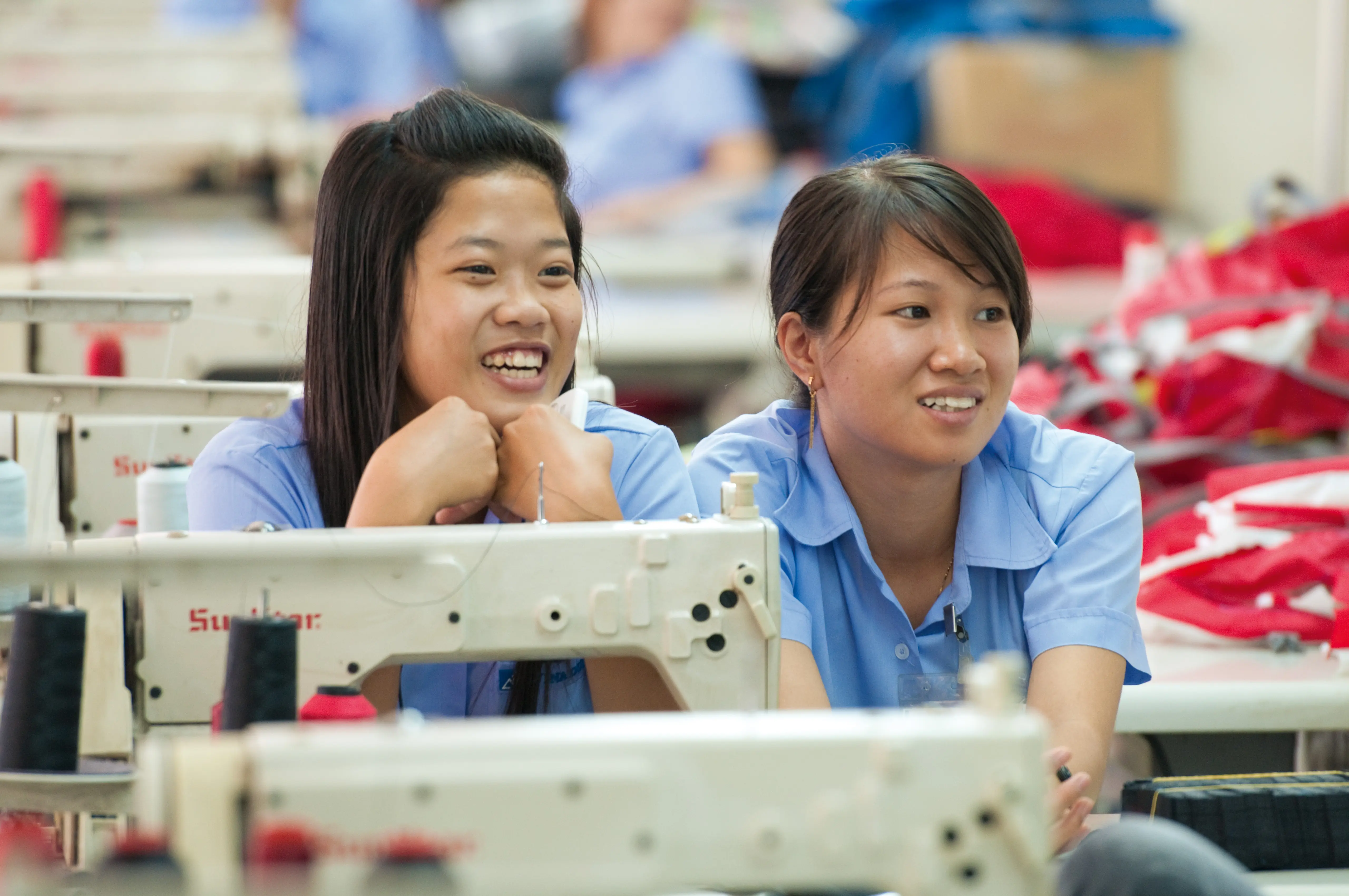 Person, Face, Head, Smile, Finger, sewing, workers, blue shirts, factory, fabric
